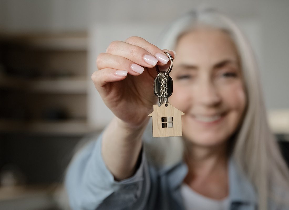 Insurance by Industry - Senior Lady Smiling at Camera While Holding a Pair of House Keys