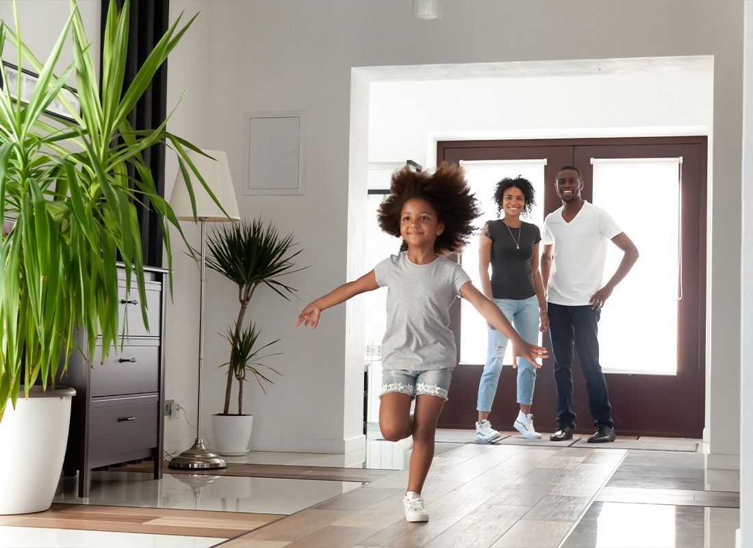 Personal Insurance - Parents Standing by the Entrance of Their Home and Smiling at Their Daughter Running Down the Walkway of Their New Home